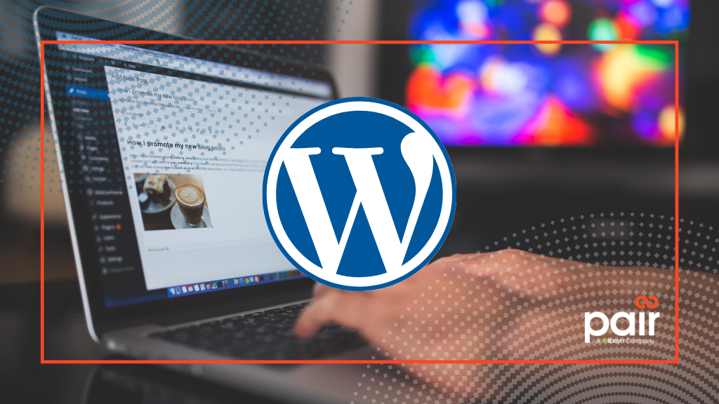 The WordPress logo in the cnter onn a blurred backdrop of hands typing on a laptop revising a website. Pair Logo in the bottom right corner.